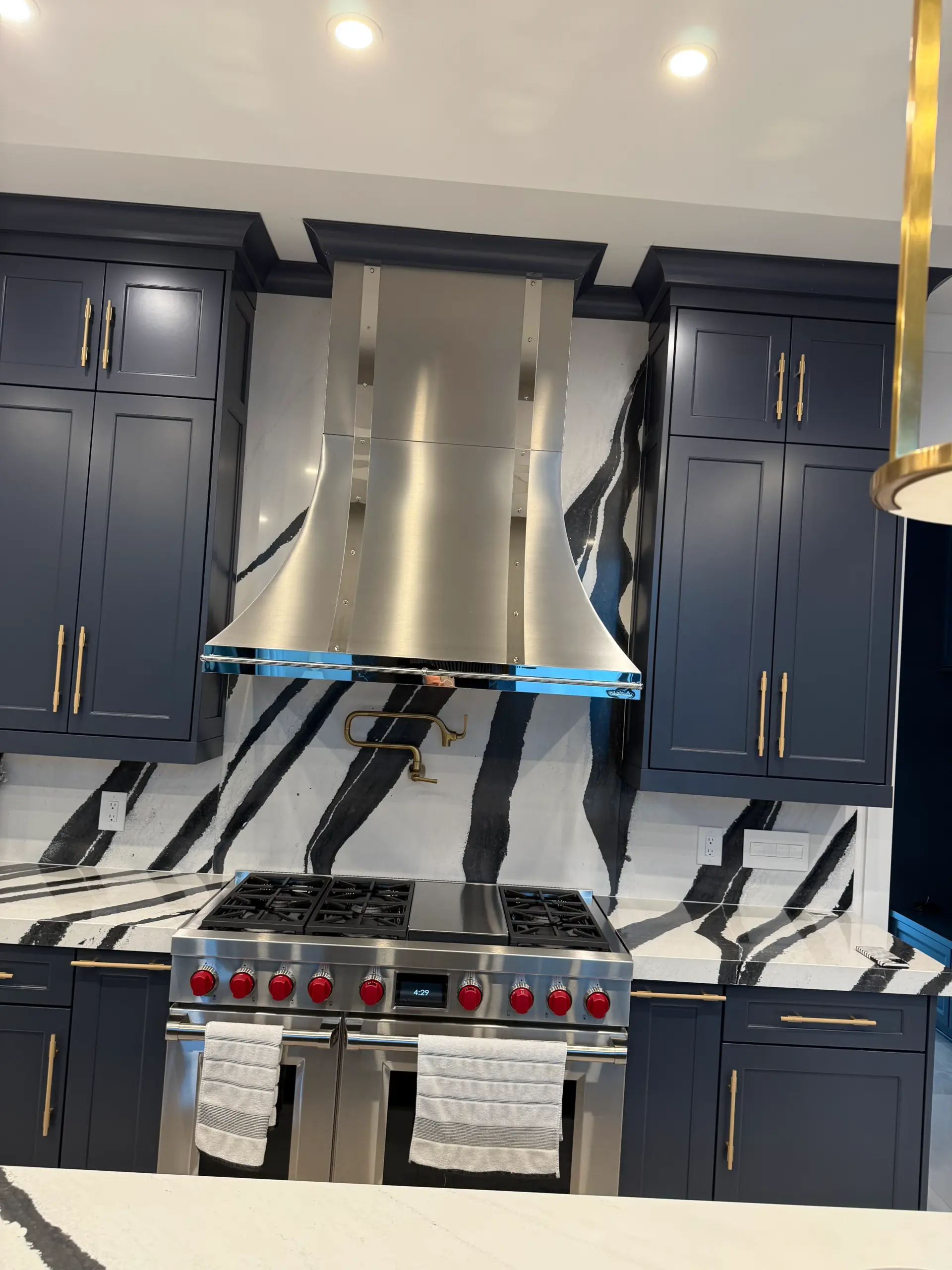 Professional kitchen range wall with dramatic black and white marble backsplash and stainless range hood in luxury home